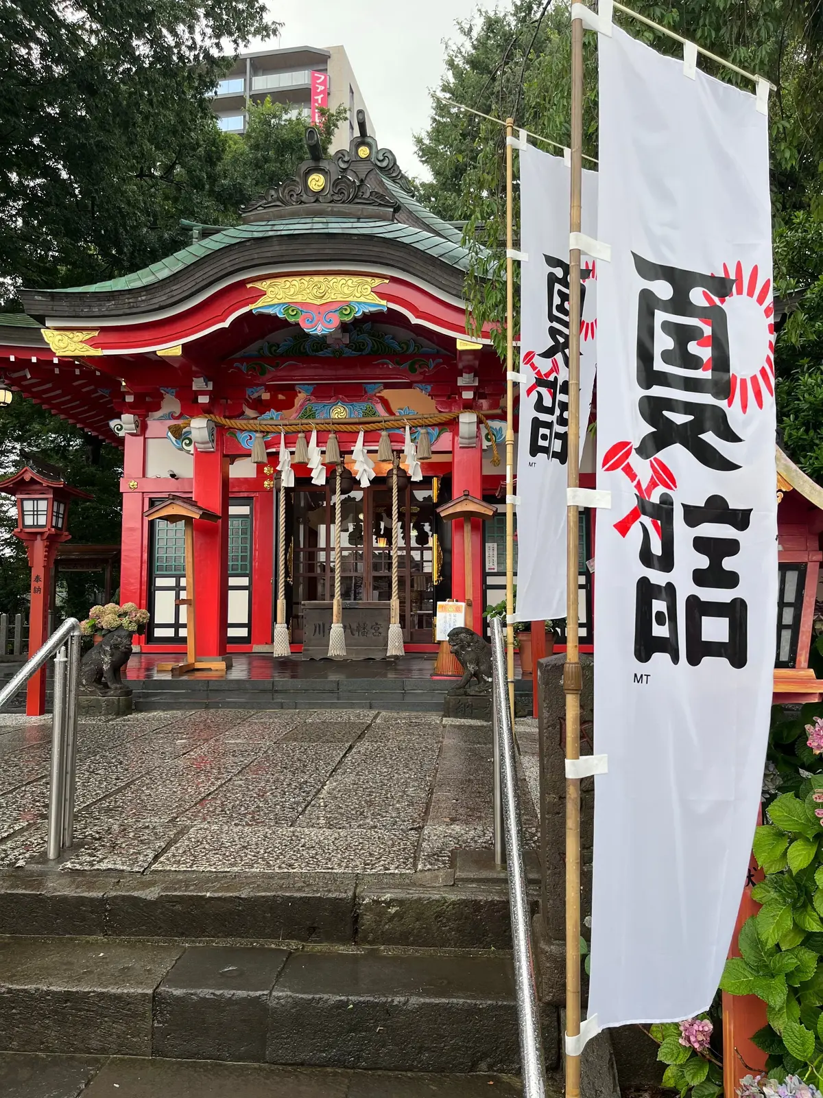 赤い装飾が施された神社鳥居、提灯、石段と手すりがある