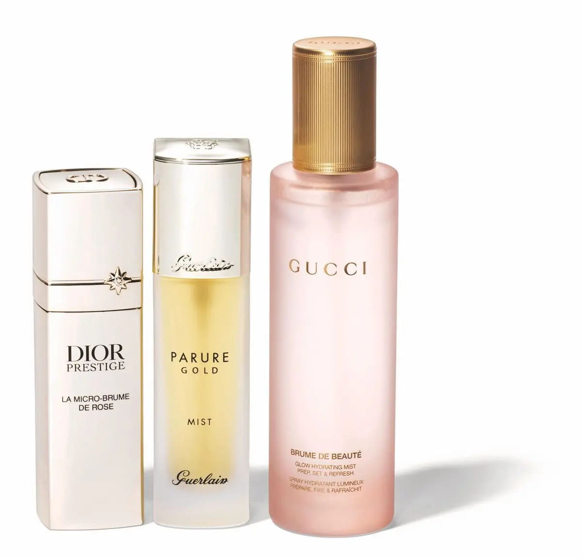 左から、Diorのローズのミスト、Guerlainのゴールドのミスト、Gucciのピンクの保湿ミストの3つの美容液ボトルが並んでいる。それぞれ異なる形状と色で、ブランドロゴが記載されている。