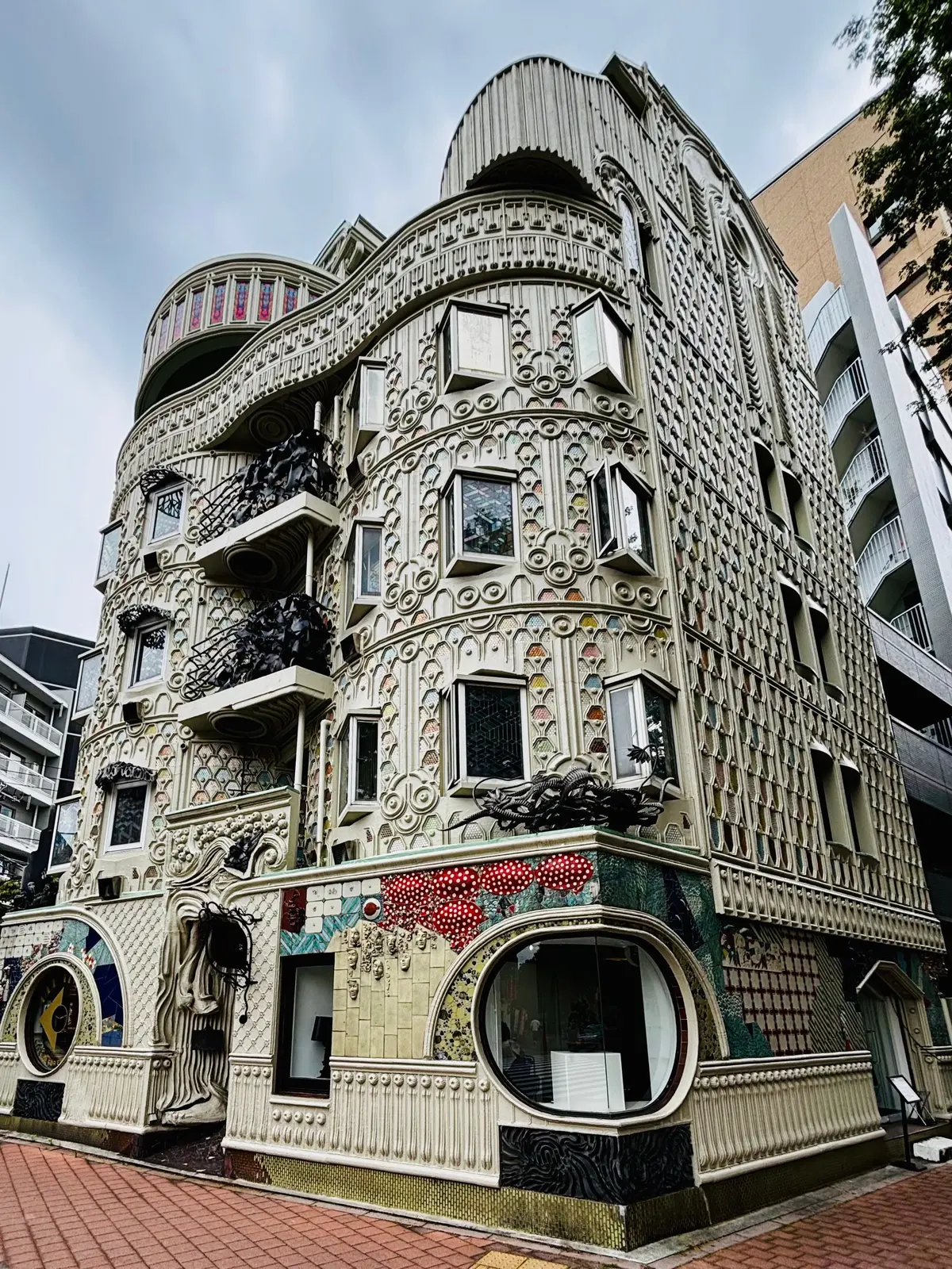 早稲田 ドラード和世陀 白い装飾が施された多層の建物で、丸い窓や細工が特徴で、赤い模様のある壁面が目立つ