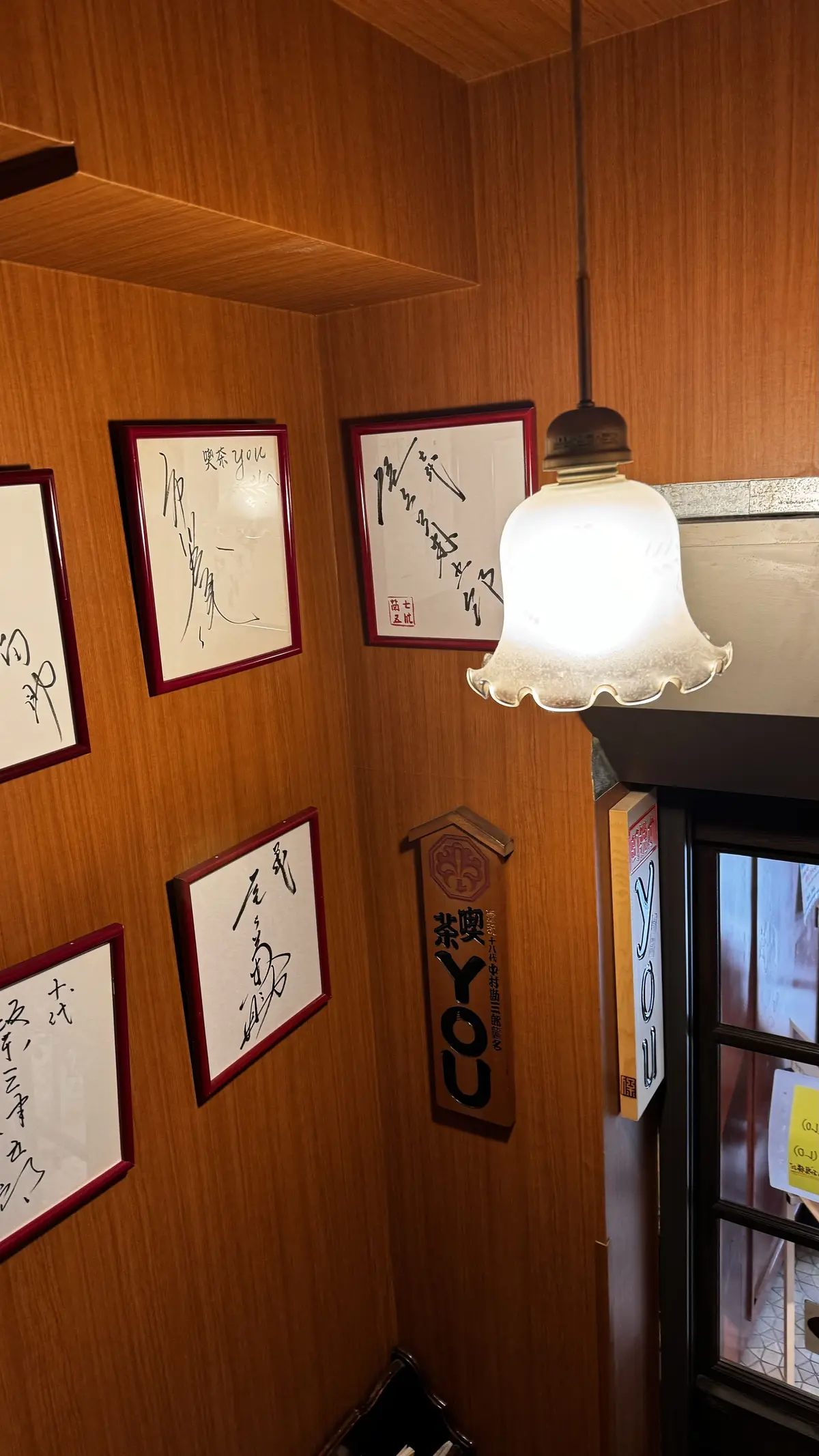木製の壁には額装された歌舞伎役者のサインが並び、ペンダントランプが下がっている狭い通路