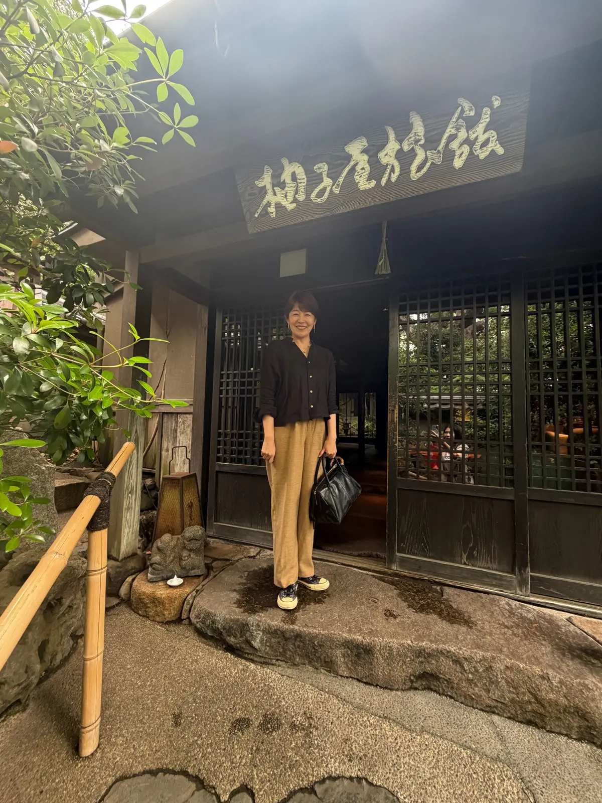 木の床と石の床が混在する伝統的な部屋で、木製のテーブルと陶器の壺が置かれています。窓から自然光が差し込み、緑の植物が配置されています。