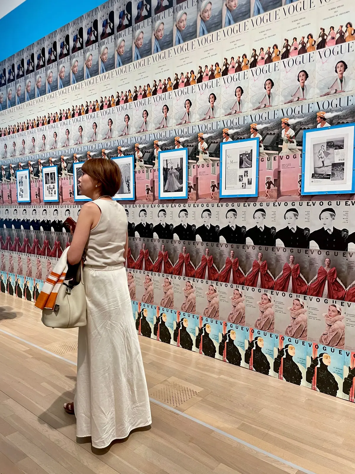 VOGUE表紙のコレクションが壁一面に並び、女性が展示を観察している