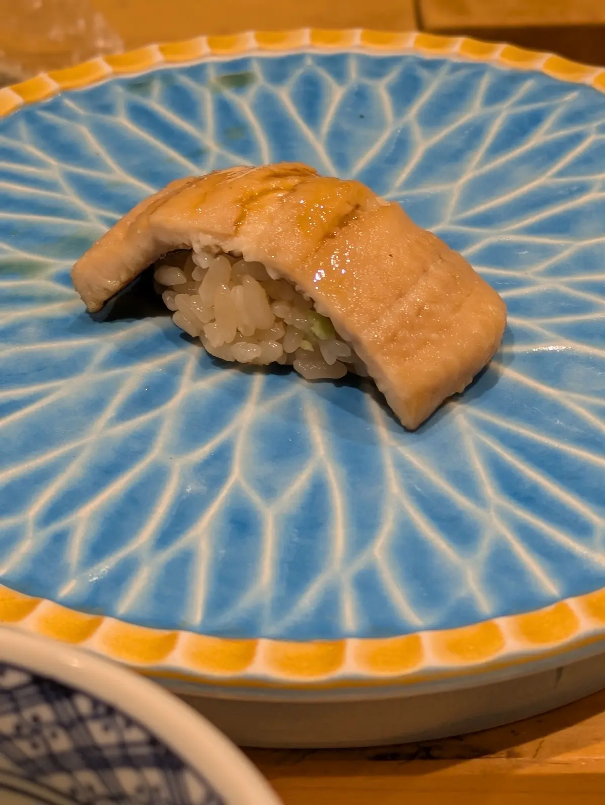 青い花模様の器に、具材が少し見えるおにぎりが乗っている