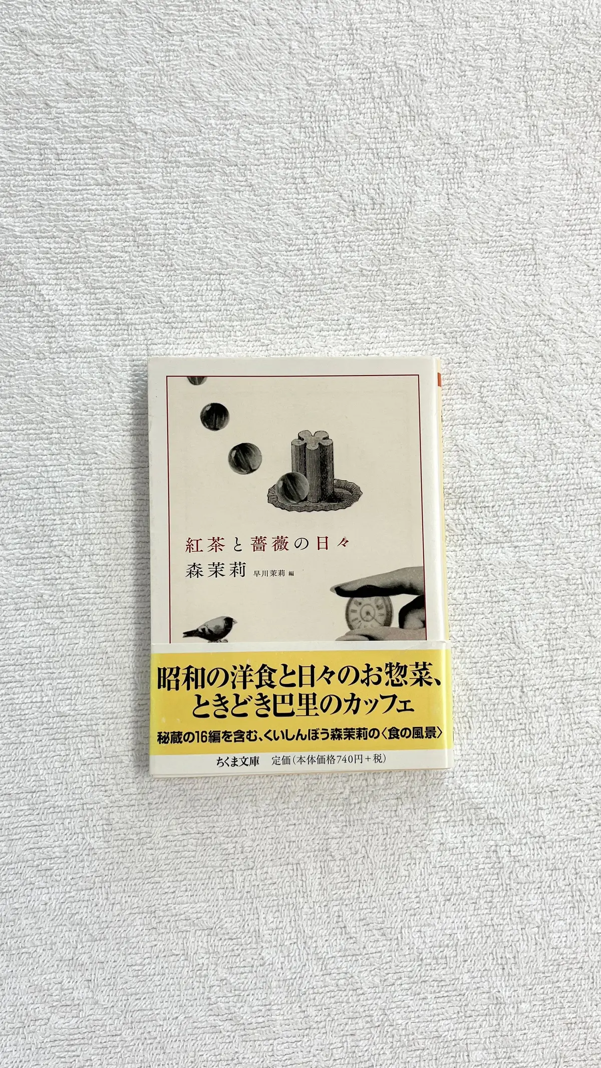 卓上に置かれた、緑と黄色のカバーを持つ書籍。タイトルは「昭和の洋食と日々のお惣菜、とくじぎく団菓のカフェ」。赤茶色と青色のイラストが配置されている。