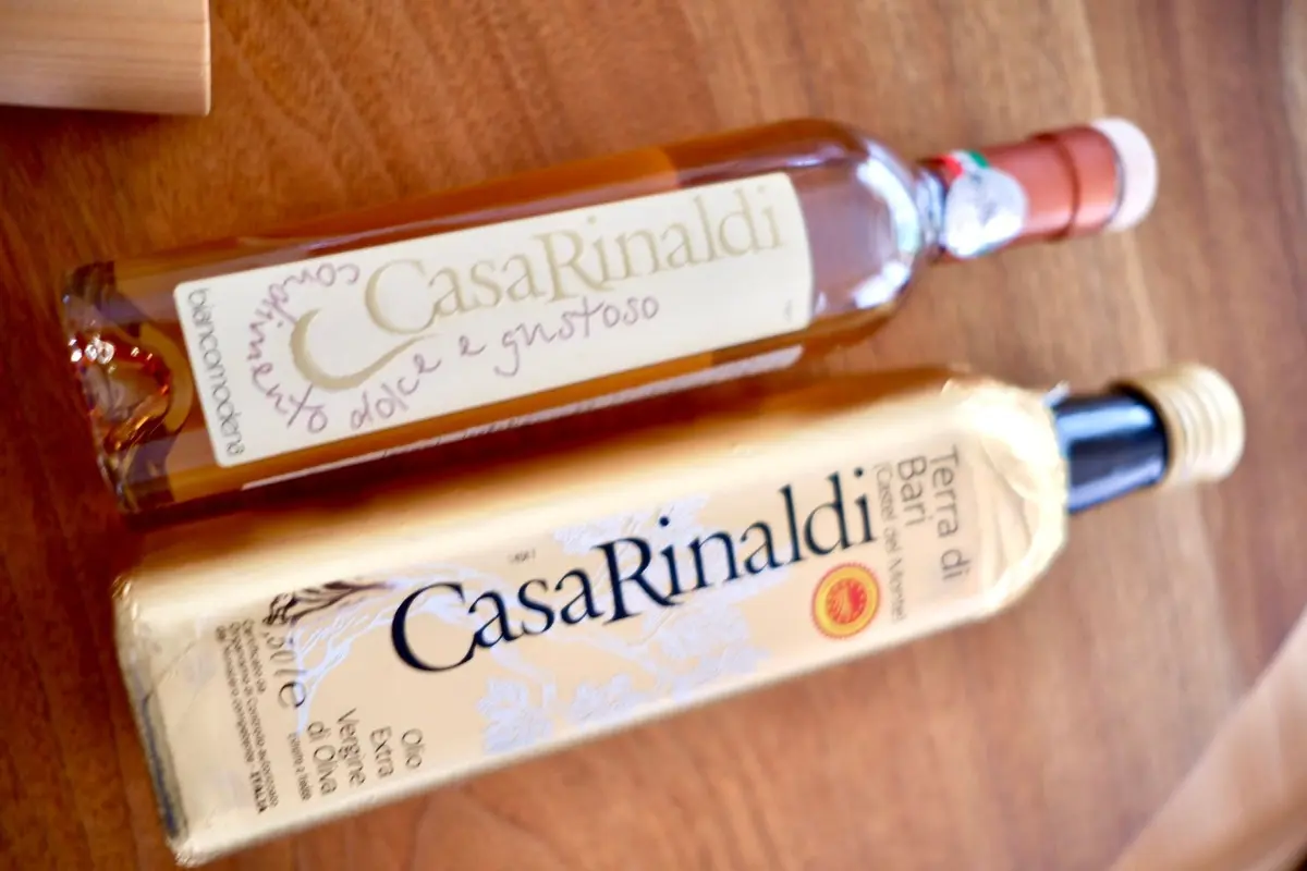 木製のテーブルに並んだ、Casa Rinaldi社のバルサミコ酢とオリーブオイルのボトル3本。左から白ワインビネガー、バルサミコ酢、エキストラバージンオリーブオイル。