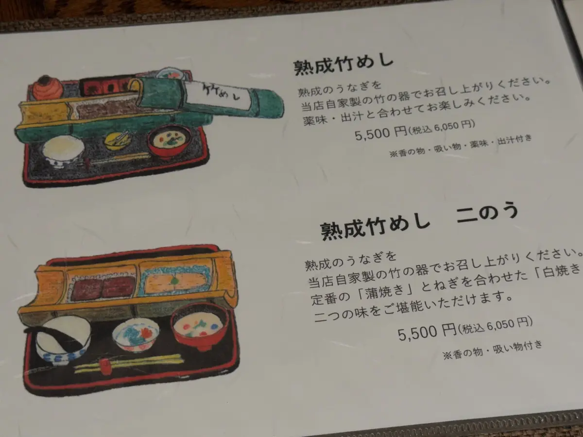 焼成竹めと呼ばれる、漆塗りの木製容器に入ったお菓子。赤、青、茶色の装飾が施され、お菓子と茶葉が添えられている。隣には二色の竹めが置かれ、それぞれ異なる色合い。価格は5,500円（税込6,050円）。