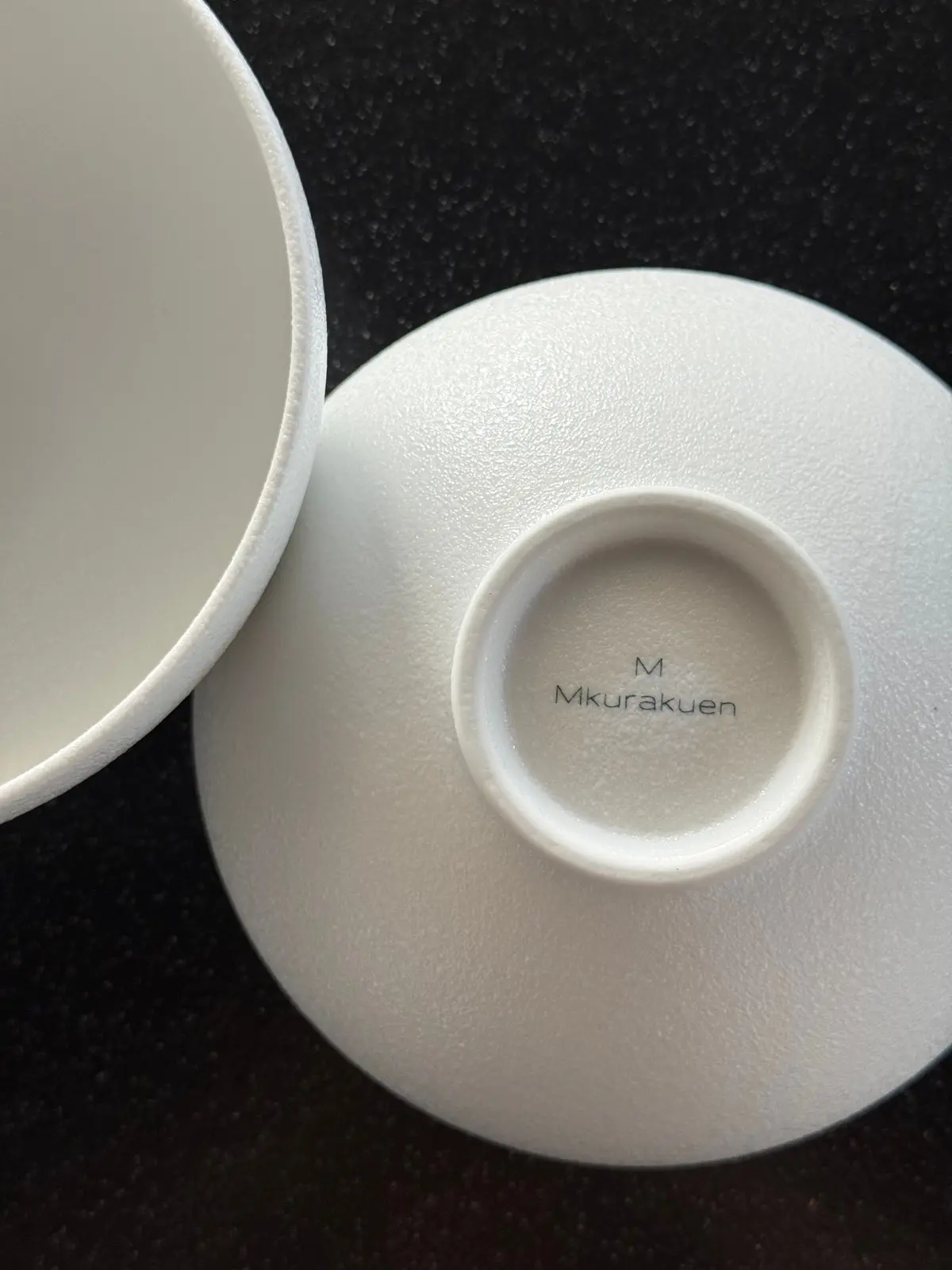 白磁の茶碗2つ。右側の茶碗の底には「M Kurakuen」の刻印がある。