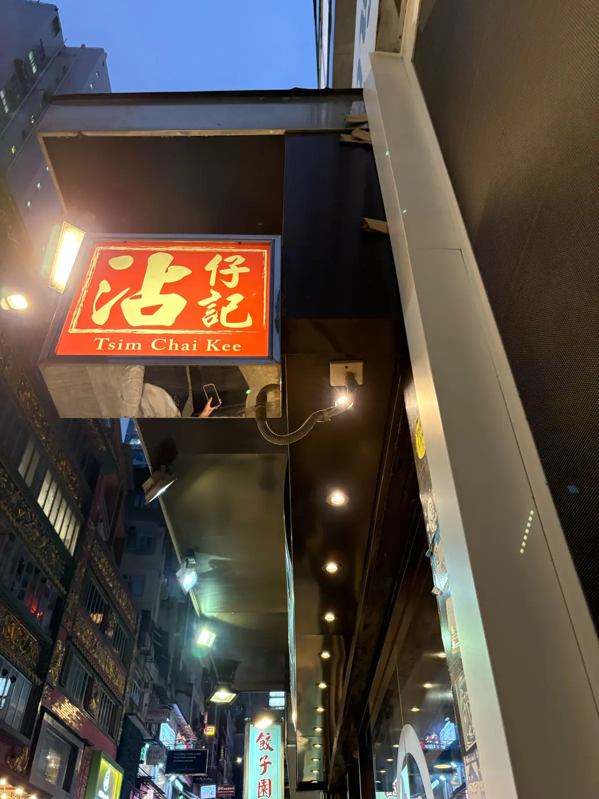 赤地に黄色の文字で「岑仔記」と書かれた看板が、夜の都市通り上に設置されている。