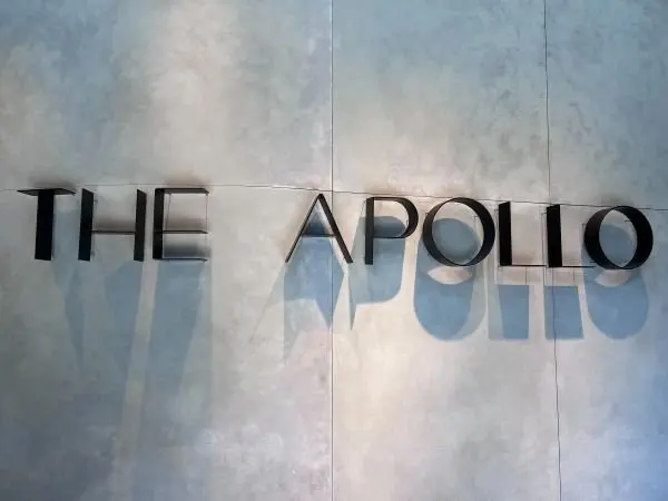 THE APOLLOという文字が灰色の大理石の壁に影を落として表示されている
