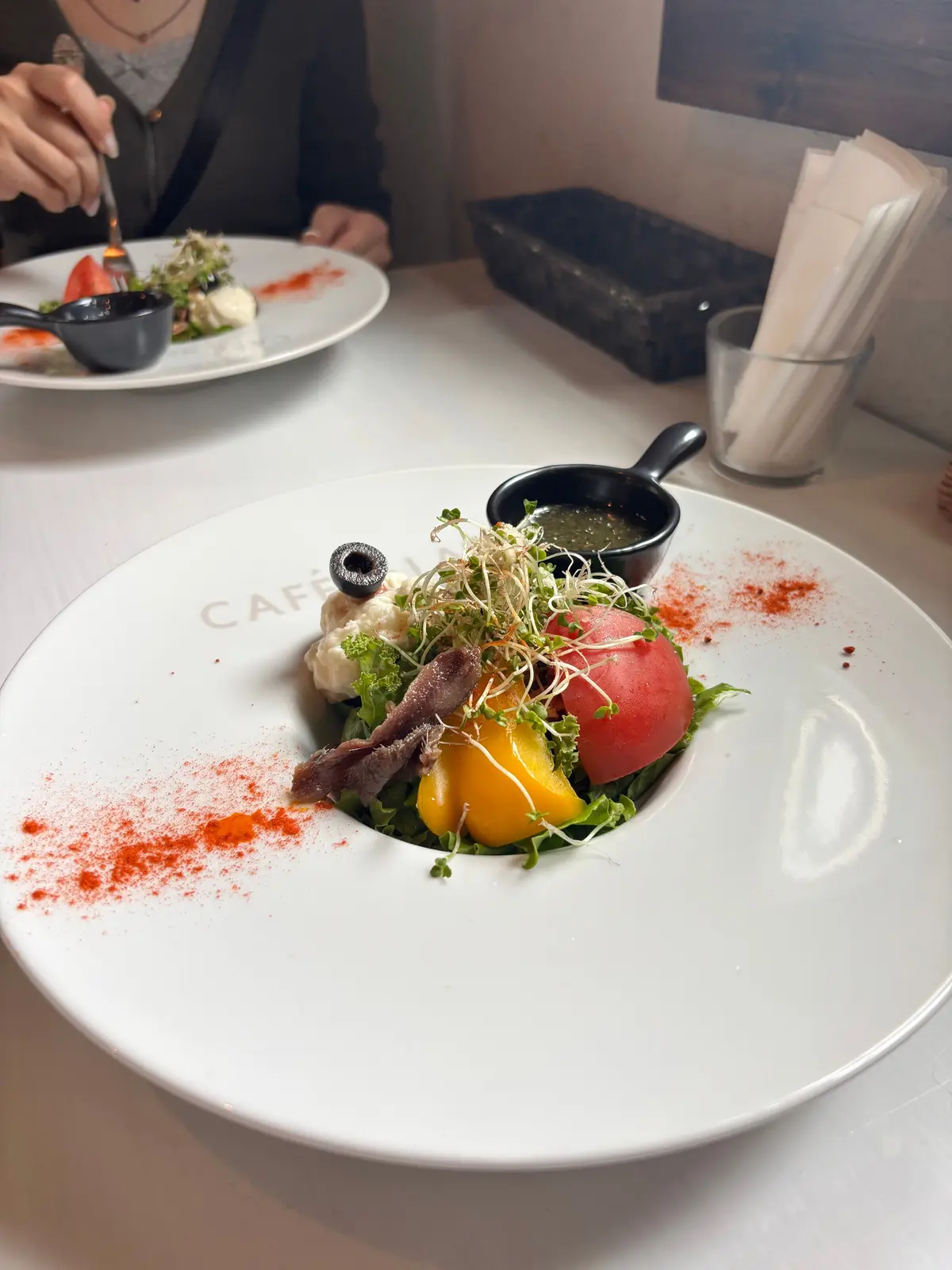 カフェドラフェットのサラダで、ドレッシングが入った黒小皿が添えられている