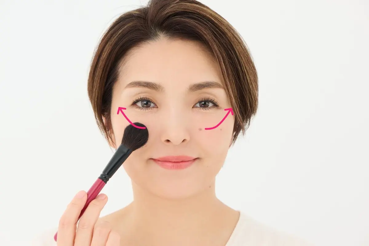 OurAge×Webエクラ　40代50代　チークの入れ方　チークをチークブラシに取り、黒目の真下で、小鼻の上側と同じ高さの位置に置き、こめかみ方向へとふわっとなで上げる