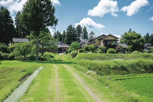 季節の花が咲き誇る手入れの行き届いた庭の向こうにたんぼ、さらに借景には高清水山が広がるおおらかな眺め。