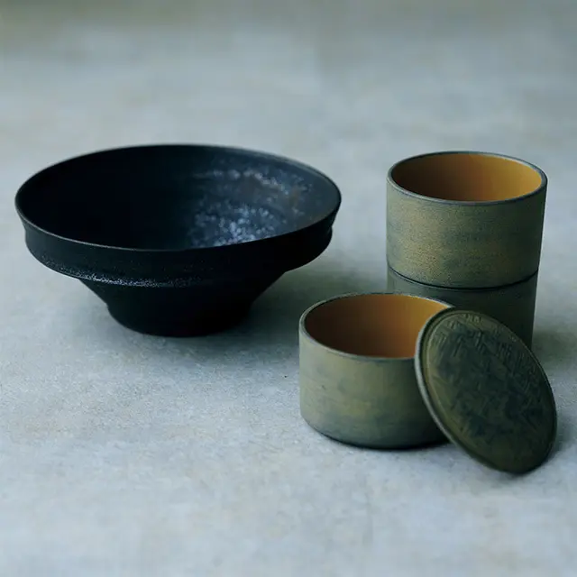 ［右］富井貴志「We Are A toms 白漆彫模様三段丸重 箱」（φ10×H17〈三段で〉㎝） ￥49,500、［左］大村剛「黒 鉢」（φ19.7×H8㎝）￥8,800