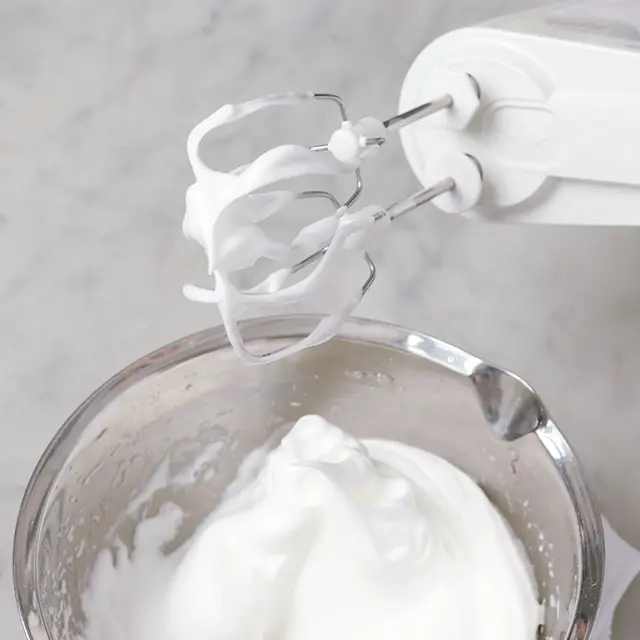 このようにピンと角が立つようになったら、 次の粉砂糖を入れるタイミング。再び1/４ 量の粉砂糖を加え、同様に泡立てる。