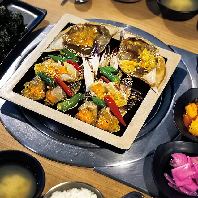 カンジャンケジャン（2匹）W75,000。カニ汁や韓国のりをまぶしたモンナニキンパという名のミニおにぎり、大根の水キムチなどがつく。カニの身はそのまま、とがった部分にも内子がぎっしり詰まった甲羅にはごはんを入れて召し上がれ！