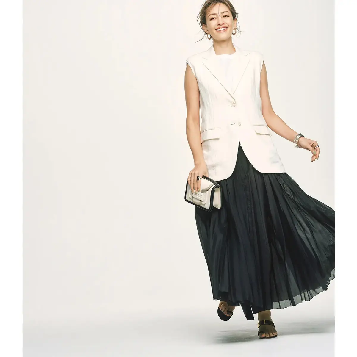 フェミニンなプリーツスカートはモノトーン配色でモードに着こなす。