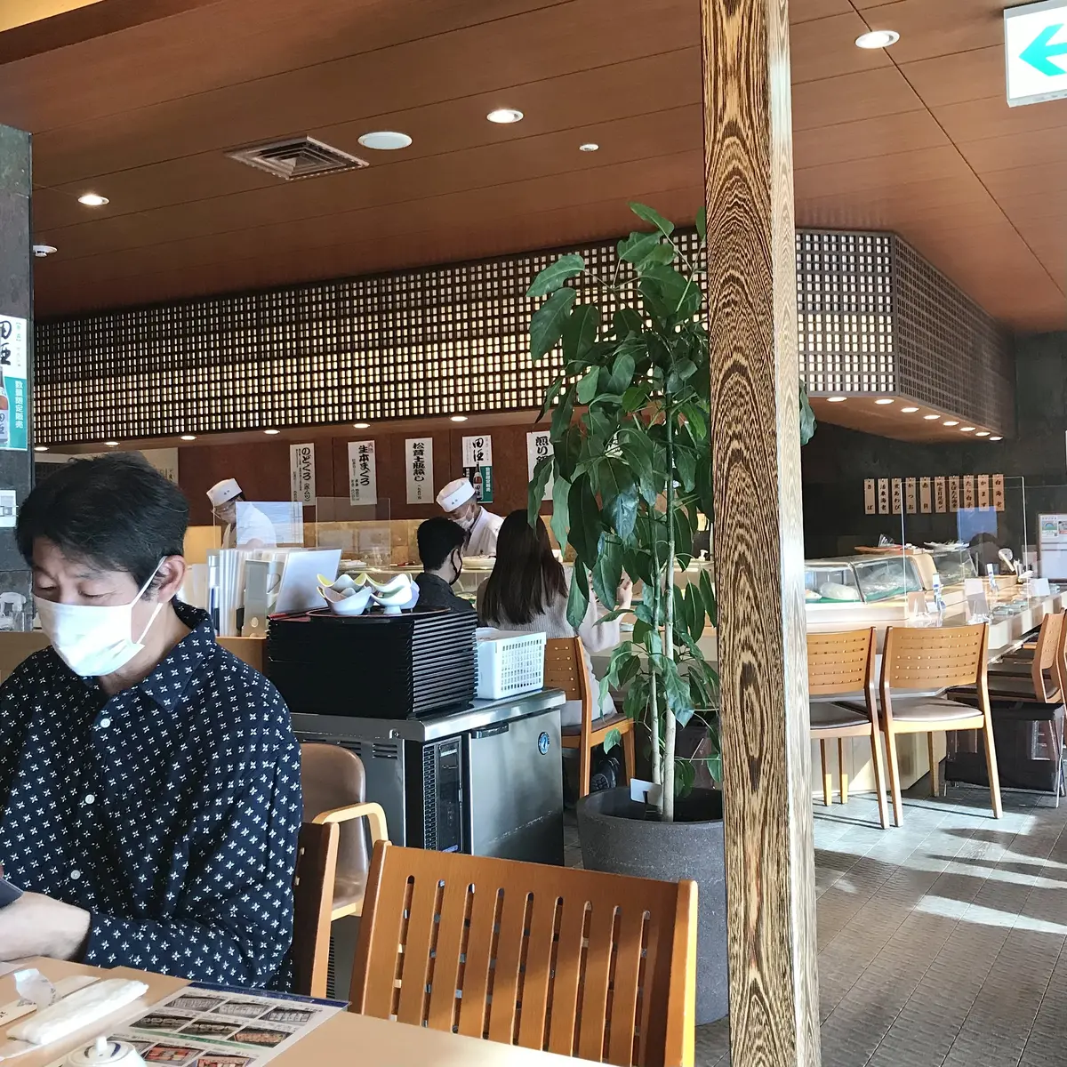 お寿司のカウンター席をバックにマスクの男性