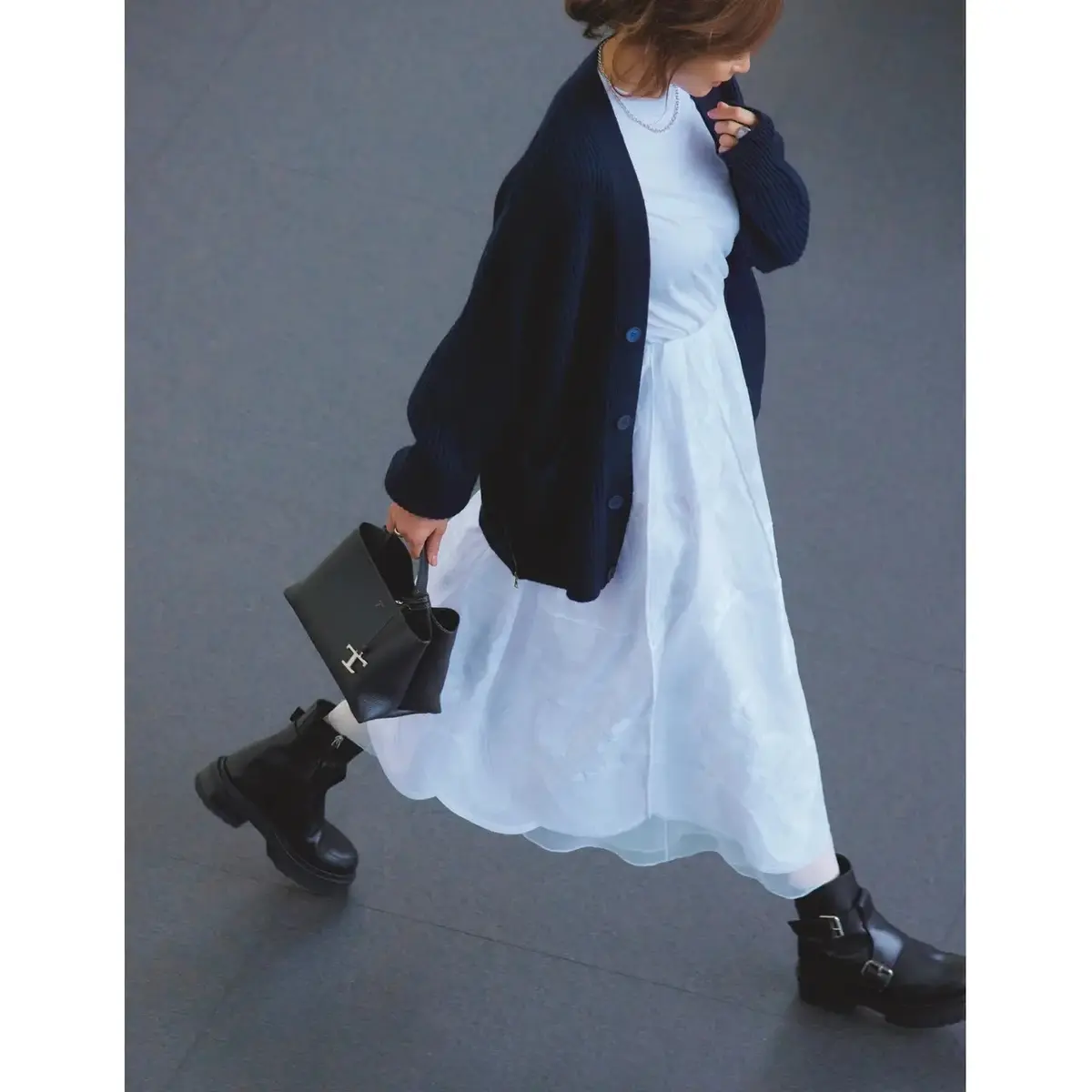 ネイビーカーディガンで、白スカートの華やかさを引き立てる。