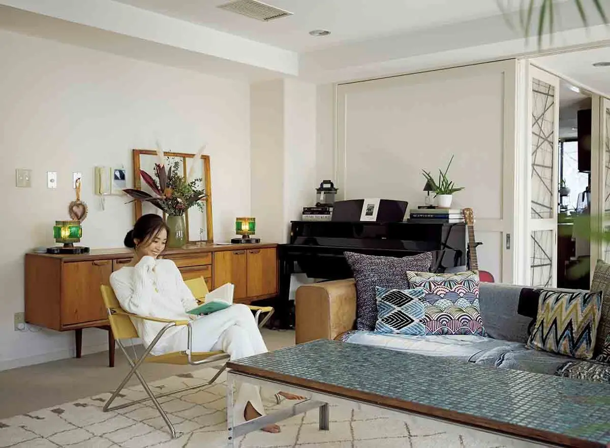 広々としたリビング。ソファはハ イクのオリジナルでレザー張り。 縁にローズウッドが施されたタイ ル天板のコーヒーテーブルはロイ ズ・アンティークス エゴイスト、 ミッドセンチュリー期のデンマー ク製チェストはルイスで購入。チ ェスト上にはフランスの窓枠や19 20年代のランプを飾った。佳子 さんが座るのは、パートナーが購 入してきたマルセルブロイヤーに よるD4フォールディングチェア