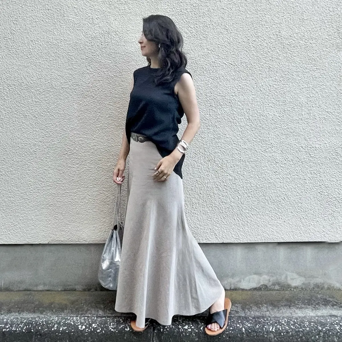黒のノースリーブブラウス、ベージュのマーメイドマキシスカート、黒のフラットサンダル、シルバーのバッグ