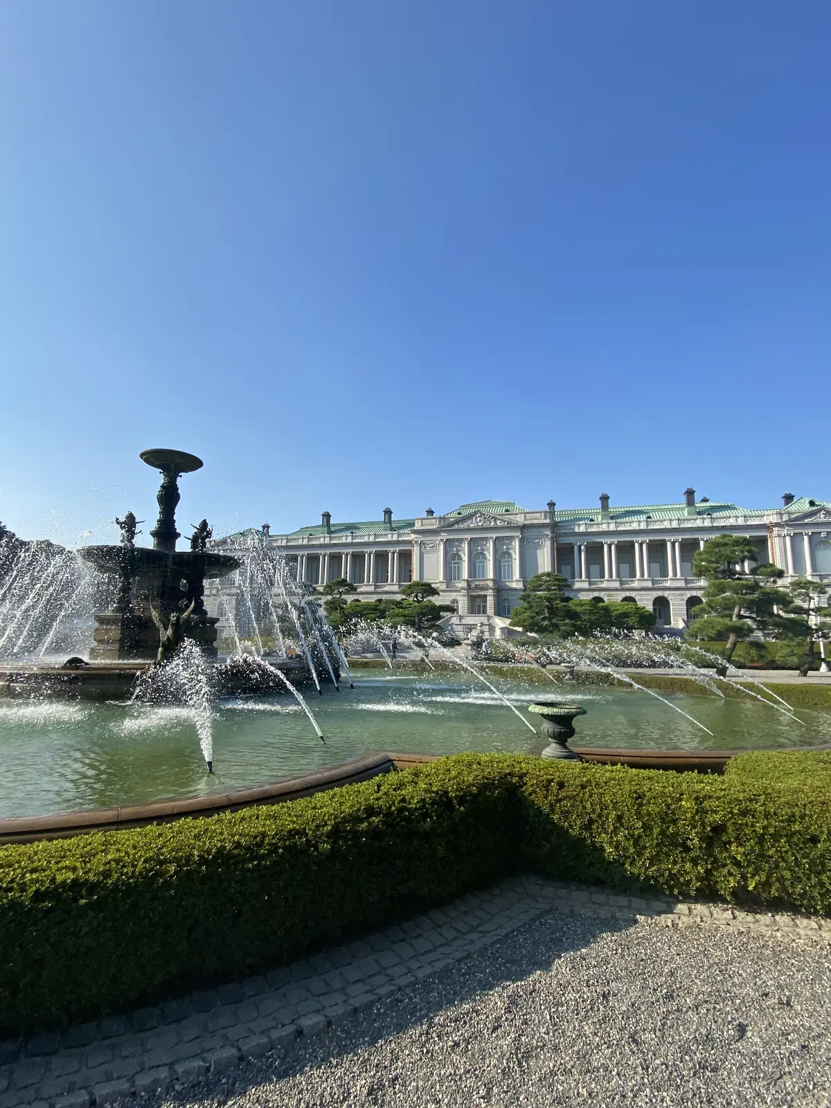 迎賓館の主庭にある噴水と、本館の外観。青空の下、水しぶきが輝いている。
