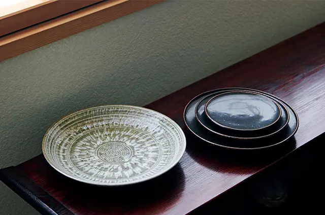 光藤佐［右］「黒釉皿 大」￥5,940、「同 中」￥4,620、「同 小」￥3,300、［左］「とびかんな皿」（φ20.5×H3.5㎝）￥7,700　