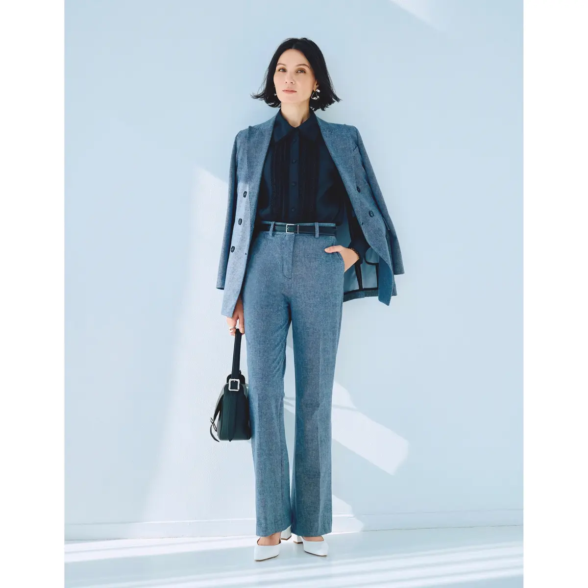 グレージャケットとパンツのセットアップにネイビーフリルシャツを合わせたコーデモデル・ 田沢美亜