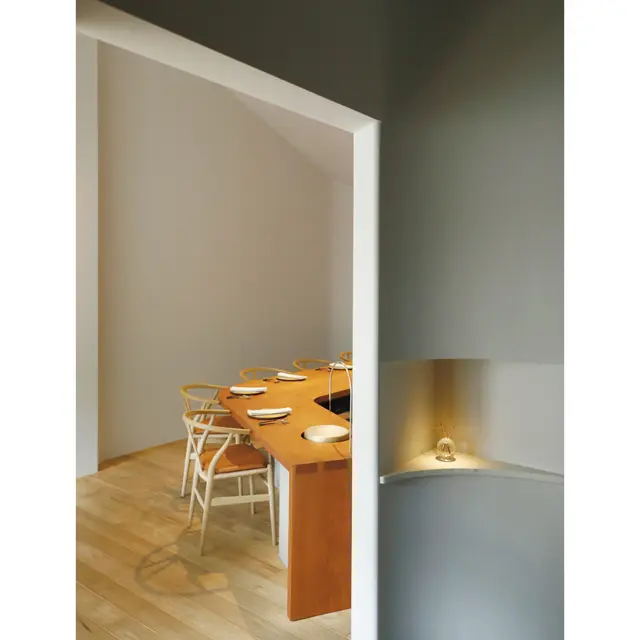 白に統一されたオープンキッチンのカウンターに無垢の家具を備える