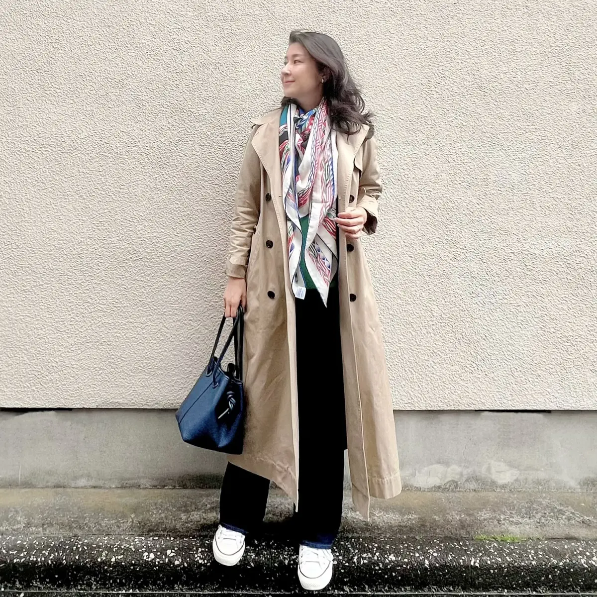 ロングトレンチコート、UNIQLOのグリーンのコットンニット、フレアーデニム、ネイビーのバッグ、大判ストール、コンバースの白のローカットスニーカー