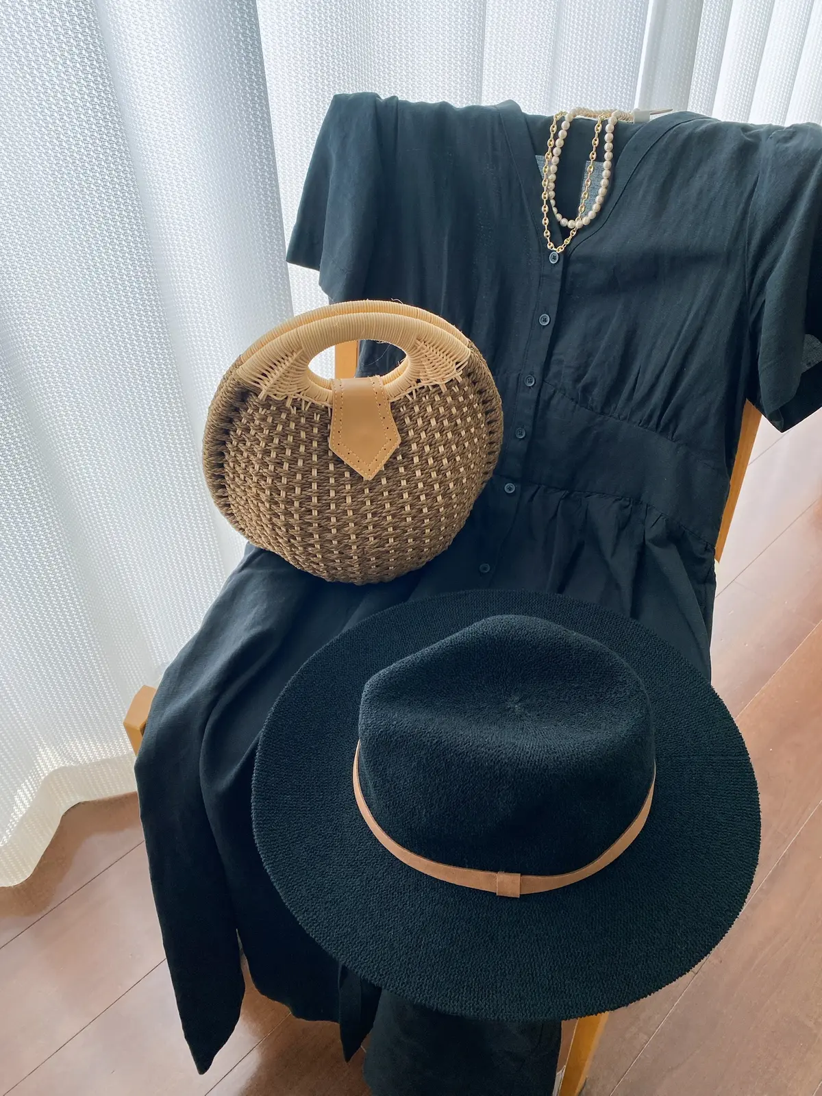 黒のユニクロリネンワンピースにラウンド型のカゴバッグとブラックハット。パールとチェーンネックレスがアクセント。