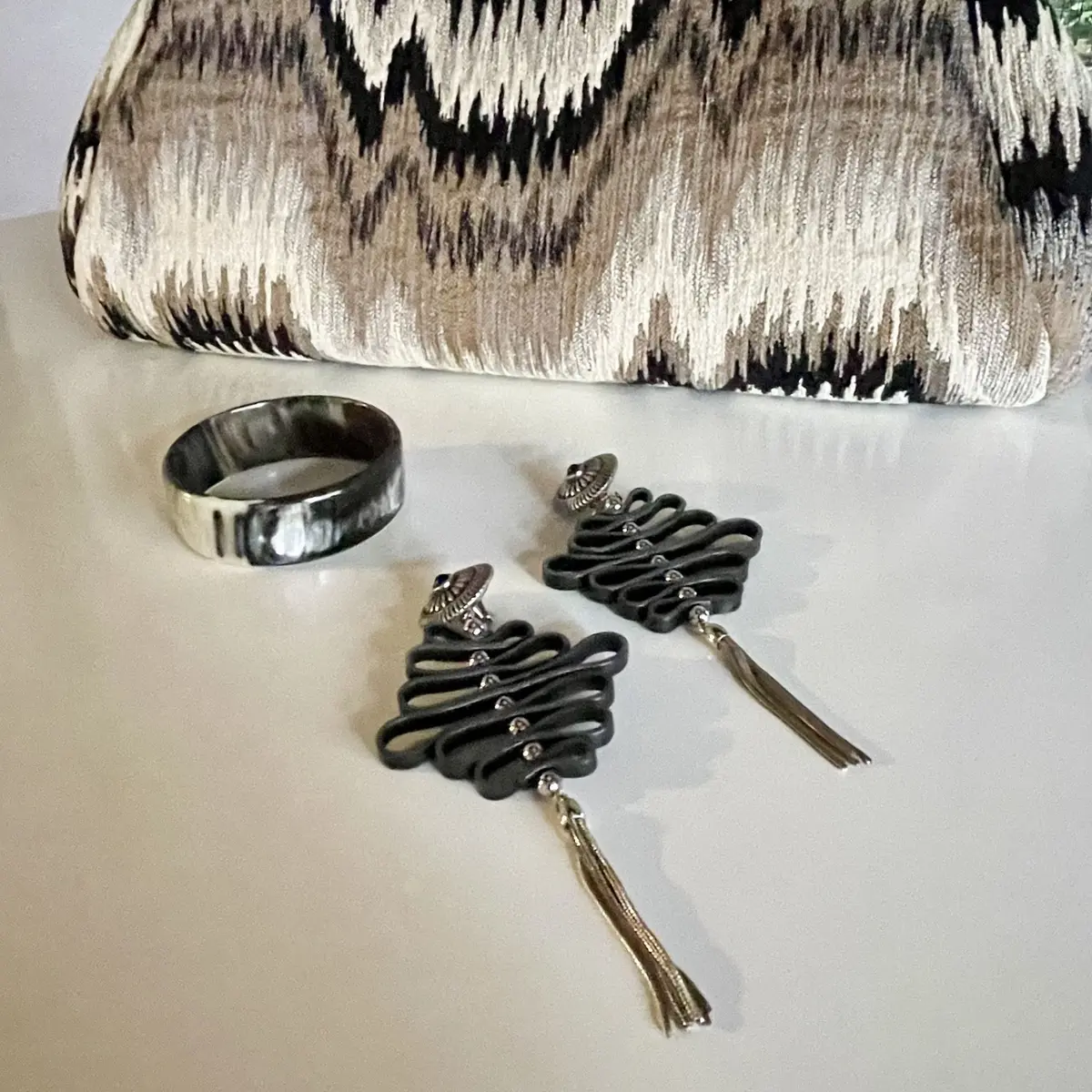 ブラック系の大ぶりイヤシング、ブラックのバングル、ブラック系の大きめクラッチバッグ