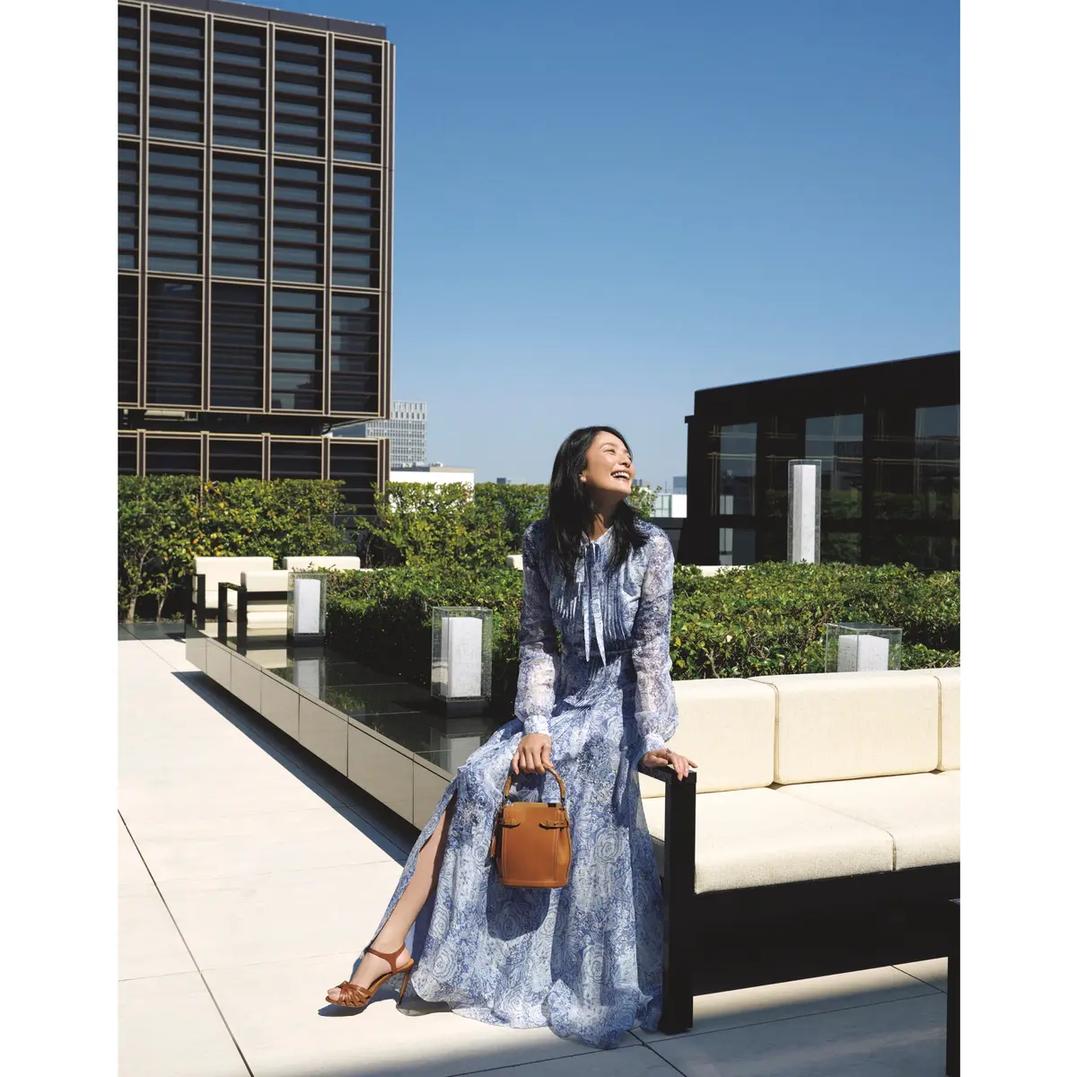ブルーペイズリープリントロングワンピースにブラウンバッグとサンダルを合わせたコーディネート　モデル・熊沢千絵