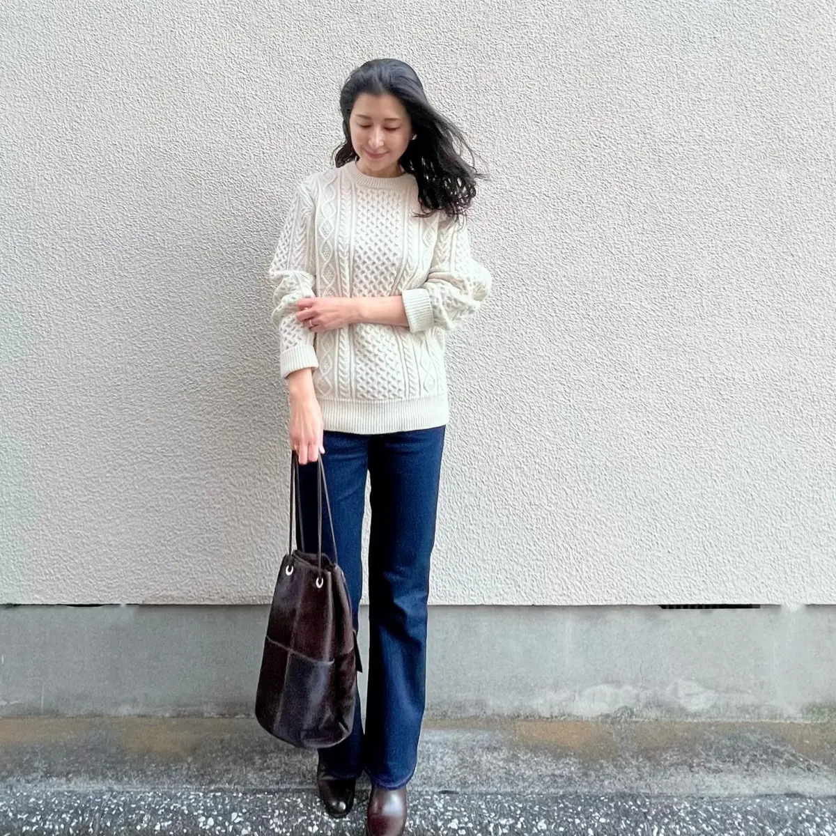 ユニクロの白アランニット、ネイビーのフレアーデニム、ブラウンのバッグ、ブラウンのショートブーツ