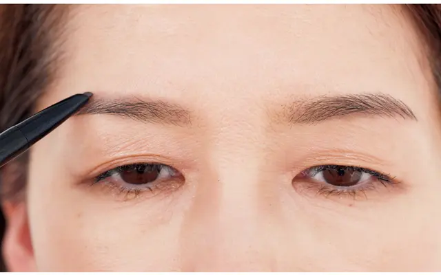 グレーペンシルで設計図のように右眉は上、左眉は下側を意識しながら描き足す。仕上げは黄み系パウダーで全体にぼかす。