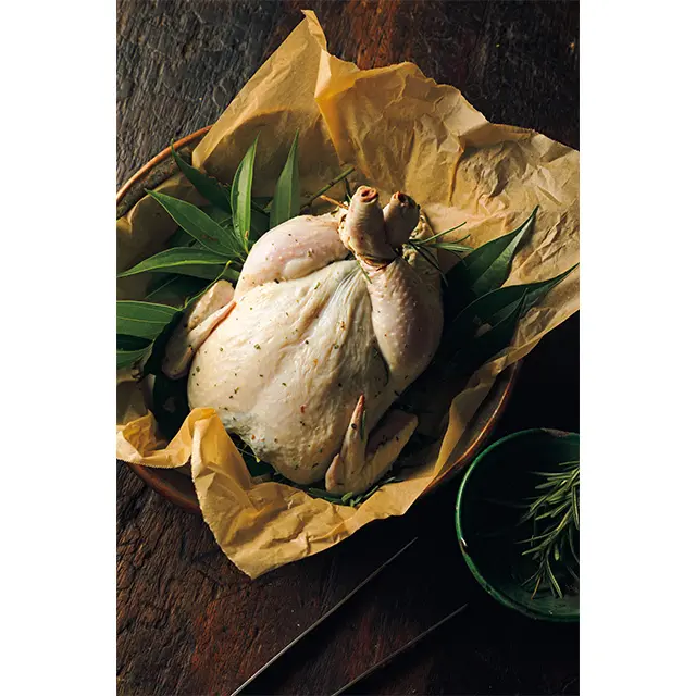 ）手で「マッサージ」して、ハーブやにんにくの風味を鶏肉にしっかりしみ込ませる。 まわりにもフレッシュハーブをたっぷり。