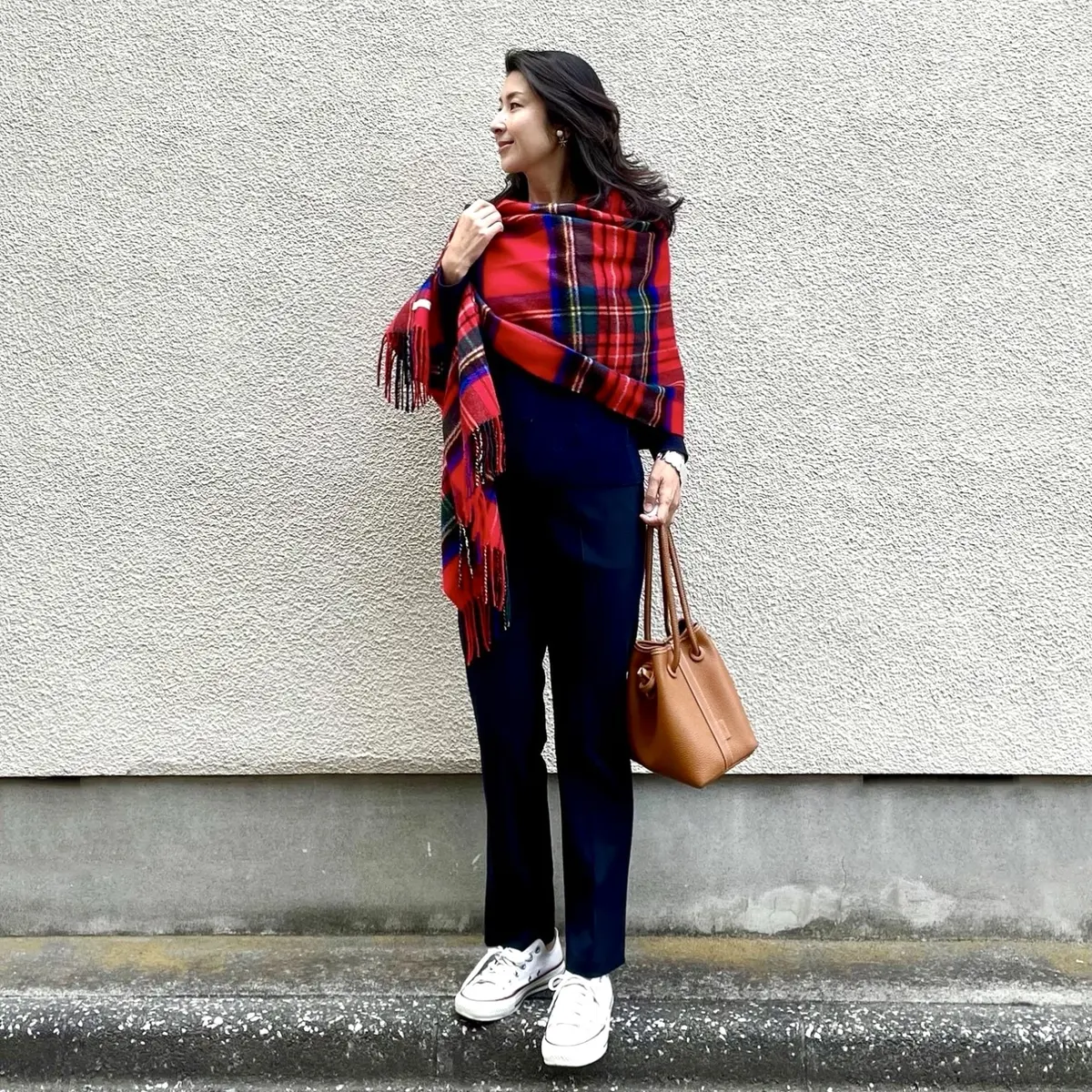 ユニクロのネイビーニットと細身ストレートパンツ、白いスニーカー、赤いチェックのストール、キャメルの小さめバッグ。