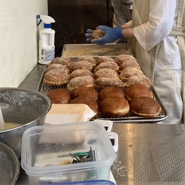 揚がったドーナツに粉をまぶしている店員