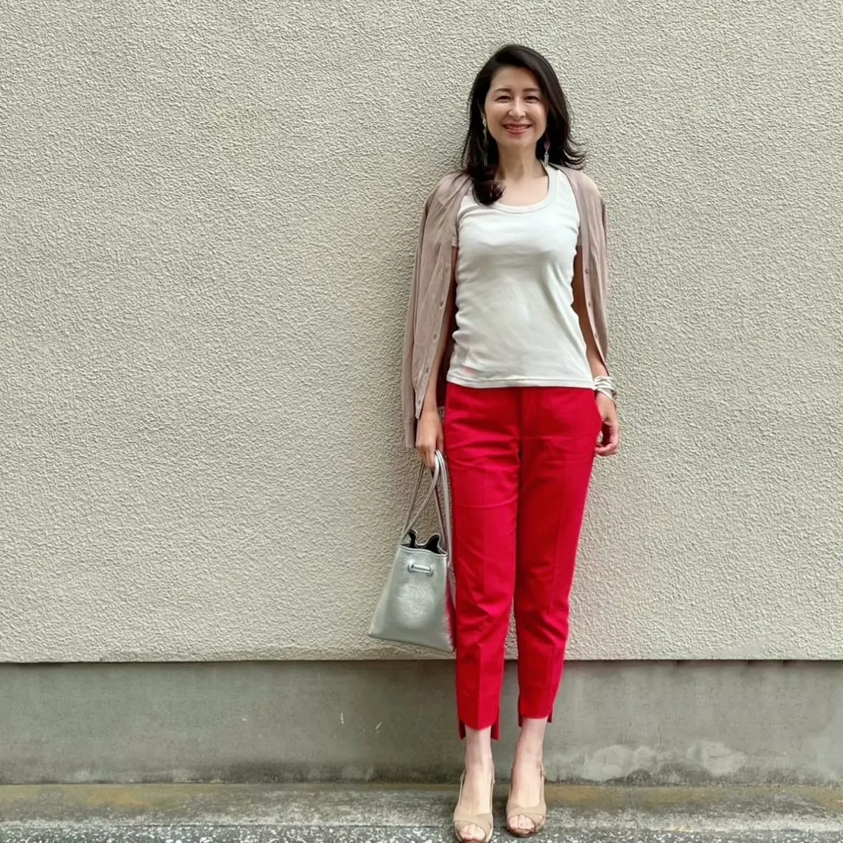 赤のクロップドパンツ、ライトベージュのTシャツ、ベージュのカーディガン、ベージュのサンダル、シルバーバッグ