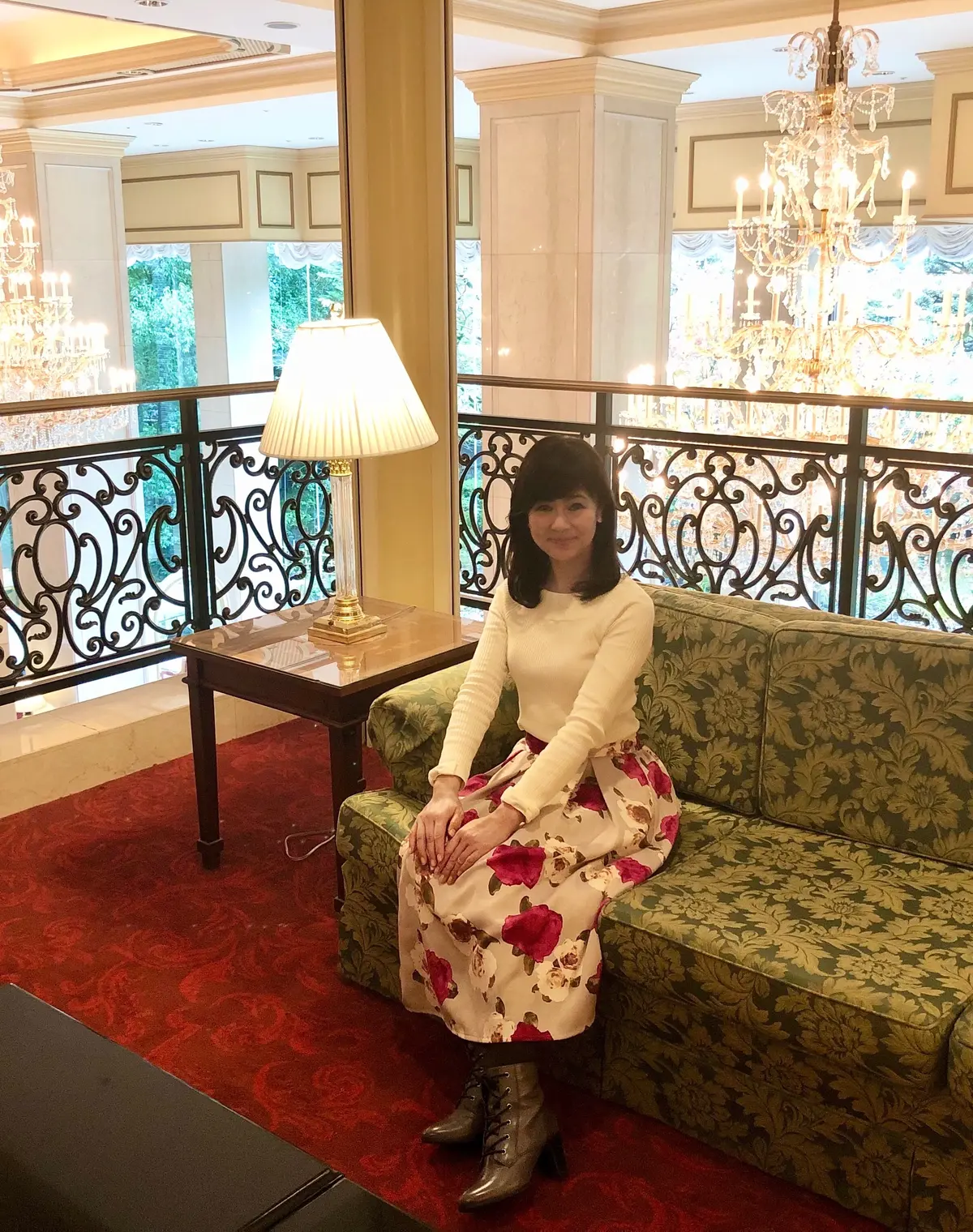 白いニットに花柄のフレアスカート。グレーのタイツ＆ブーツ。ソファーにて。