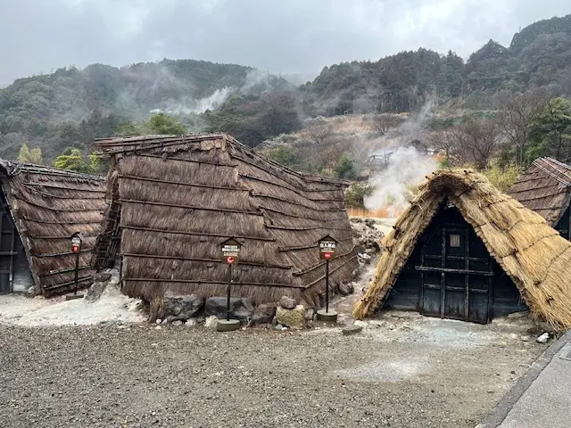 茅葺屋根の湯の花小屋が並びます。湯けむり。