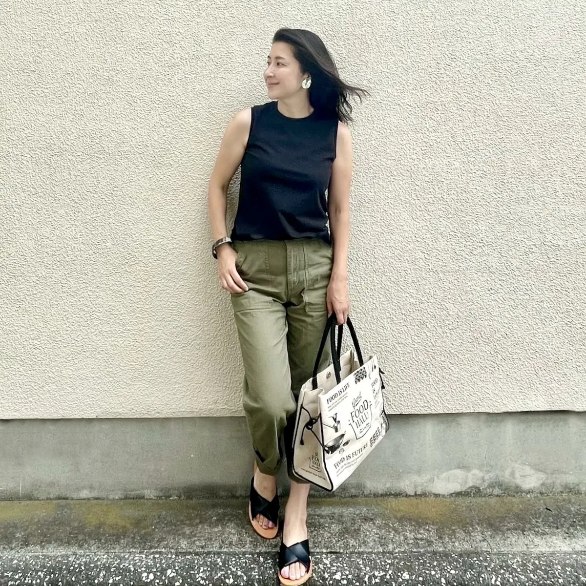黒Tシャツ、カーキのベイカーパンツ、黒サンダル、エコバッグ
