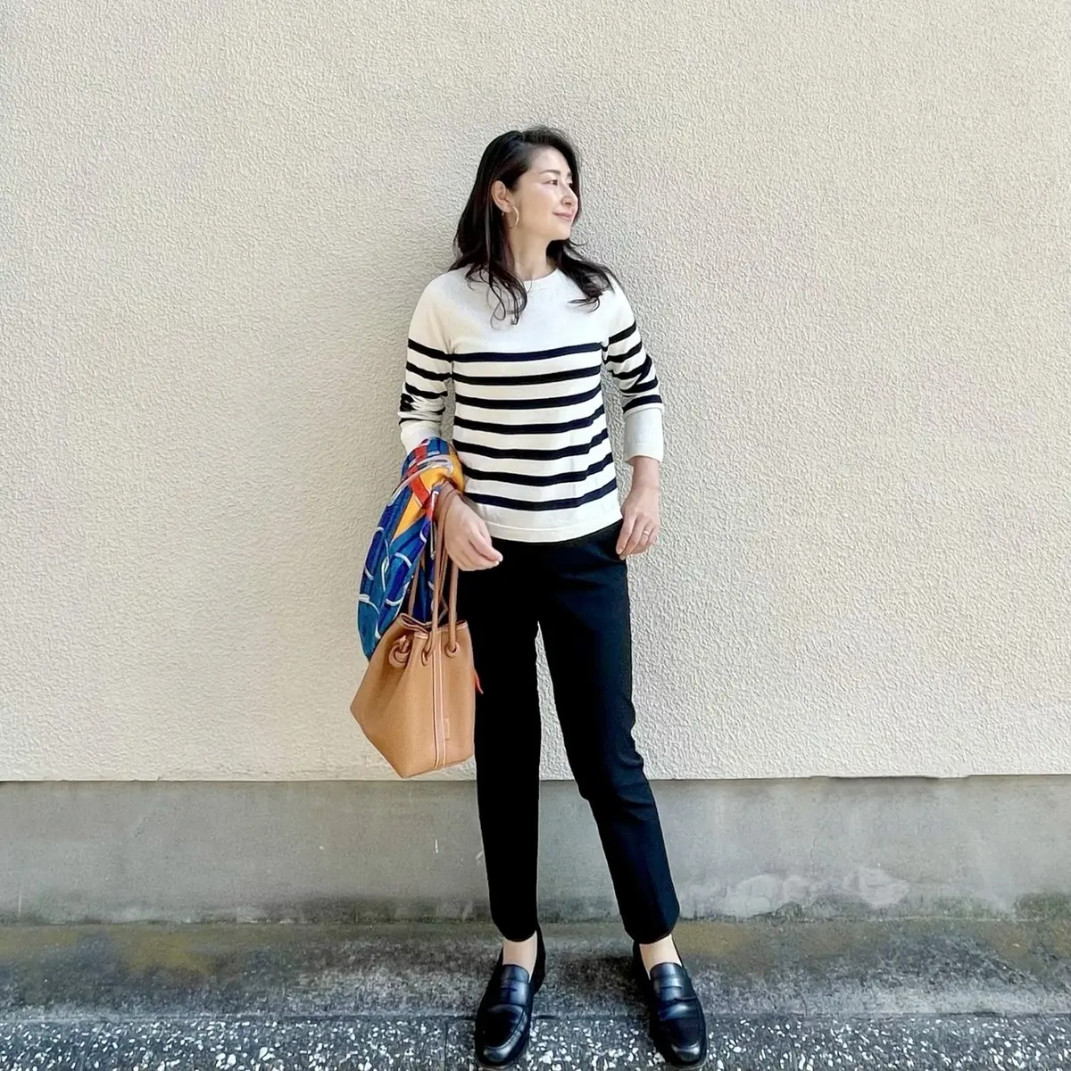 パネルボーダーニット、黒パンツ、くすみオレンジのバッグ、黒のローファー