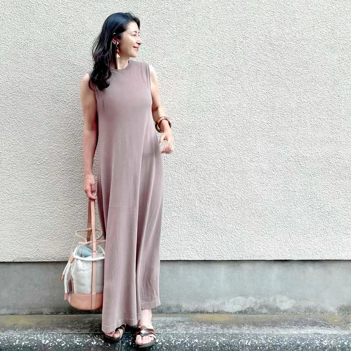 ベージュのロングニットワンピース、ブラウン系カジュアルサンダル、PVCとレザーのバッグ