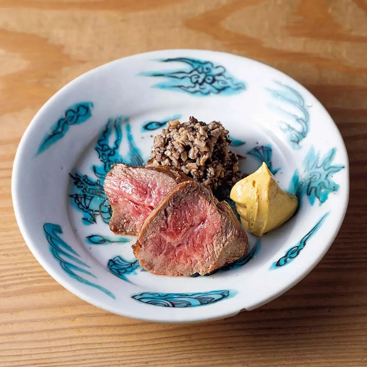 「和牛ラムシンの炭火焼のきのこソース添え」。器は明末期のもの