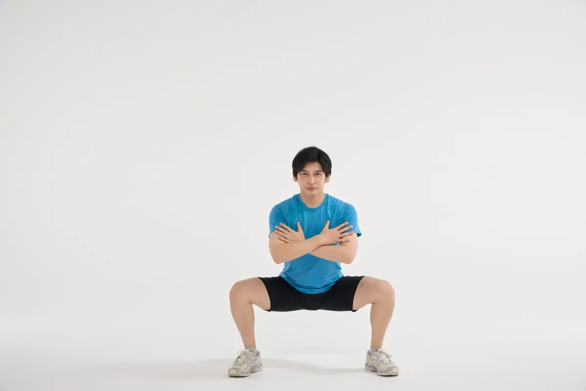 ② そのままお尻を膝の高さくらいまで下ろす。次に、内ももとお尻をギューッと締めながら立ち上がる。この①②を繰り返す。10回×3セット。太ももが床と平行になるくらいまでしゃがむのが理想的だが、できない人は浅くしゃがんで行い、慣れてきたら徐々に深くしていけばOK。