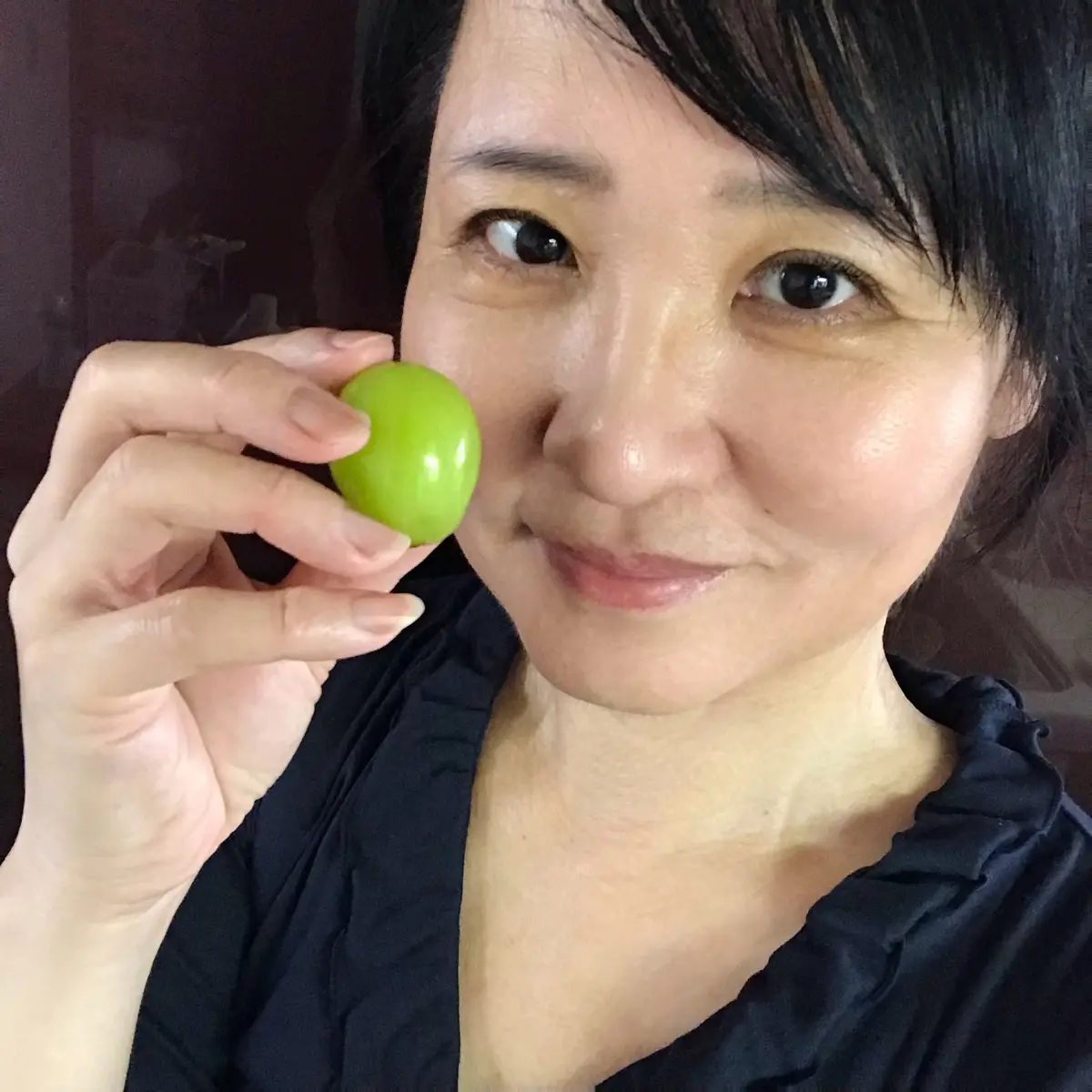 大きなシャインマスカットの粒を摘まむ女性