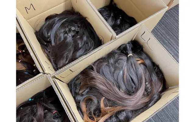 髪の毛は長さによって仕分けされ、工場でトリートメント処理を行う