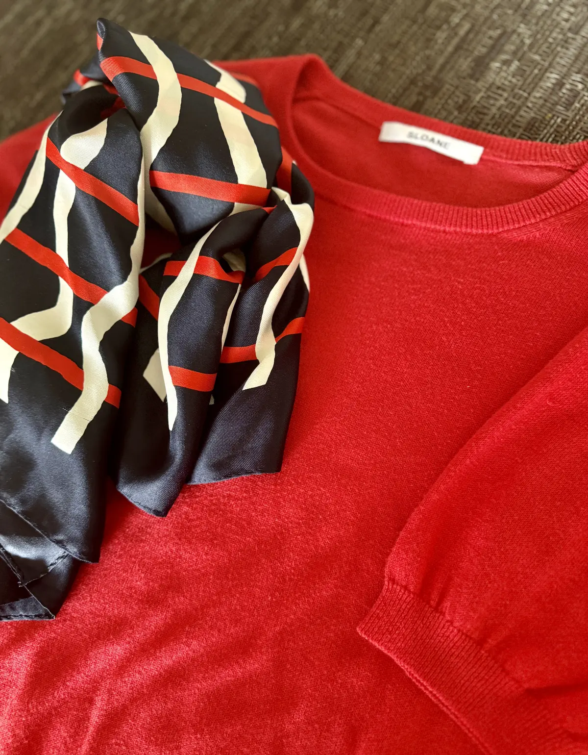 赤ニットに合わせて華やかなアクセントを加えてくれるスカーフをベルト風に