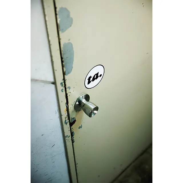 看 板はなし。古いビルの階段を上がった先にある、 ドアに貼られた小さなロゴステッカーが目印