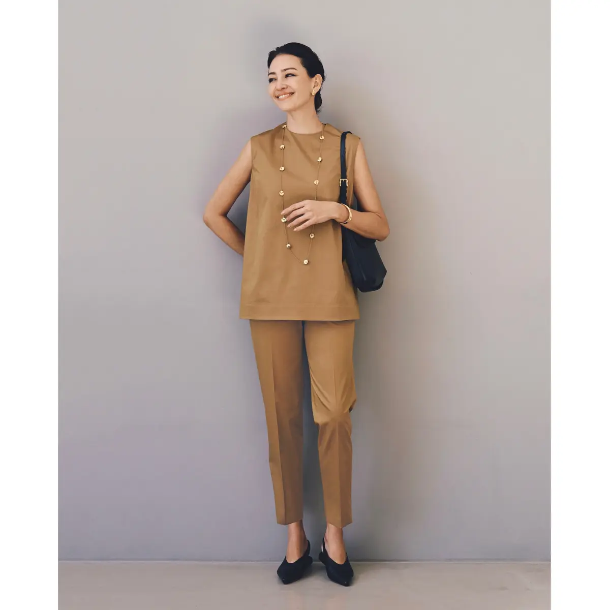 キャメルカラーのノースリーブトップスとスリムパンツのセットアップに黒バッグ&パンプスを合わせたコーディネート　モデル・RINA